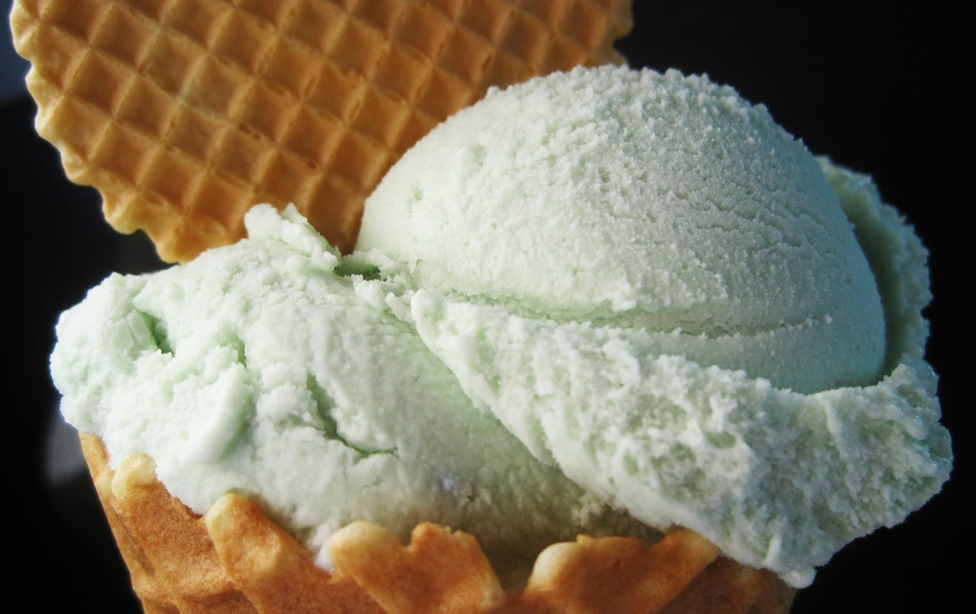 Pale green mint ice cream scoops nestled in a waffle cone
